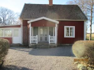 a small red house with a white door at Stuga Olstorp in Skänninge