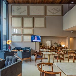 ein Restaurant mit Tischen und Stühlen und einem Flachbildfernseher in der Unterkunft Lux Lisboa Park in Lissabon