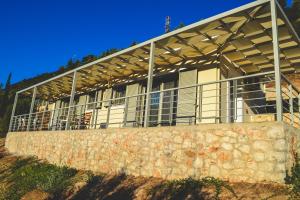 a building on top of a hill with a stone wall at Av Apartment in Agios Nikitas