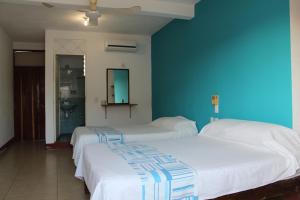 two beds in a room with a blue wall at Hotel Carruiz in Puerto Escondido