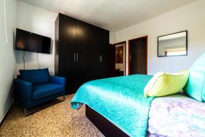 a bedroom with a bed and a blue chair at CASA LUJAN in Tijarafe