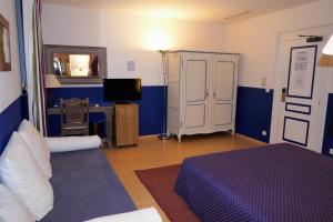 een kamer met een bed, een bureau en een televisie bij Hotel Moderne Et Pigeon in Limoux