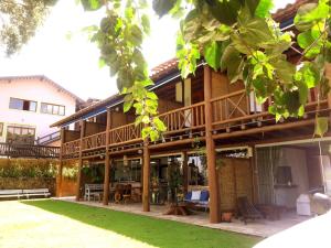 a large house with a deck and a yard at Gidu Ilhabela in Ilhabela