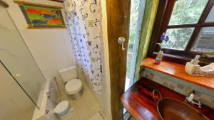 a bathroom with a sink and a toilet and a window at Casa do Joca - Ilhabela in Ilhabela