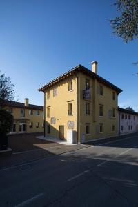 un grand bâtiment jaune sur le côté d'une rue dans l'établissement Hotel C25, à Ponzano Veneto