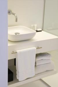 
a white sink sitting under a mirror next to a towel rack at Leopold5 Luxe-Design Apartment in Ostend
