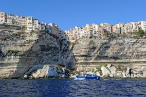 a boat on the water in front of a cliff at Résidence hôtelière A TRAMA in Bonifacio