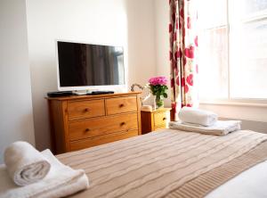 a bedroom with a bed with a television on a dresser at 1A, Opera House 1st Floor by Indigo Flats in London