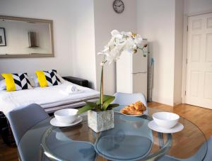 a living room with a glass table and a bed at 1A, Opera House 1st Floor by Indigo Flats in London