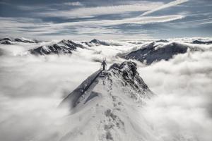 una persona parada en la cima de una montaña sobre las nubes en Hubertus Dependance en Obertauern