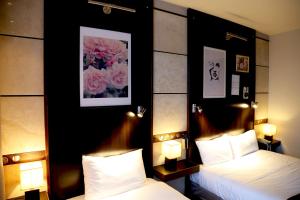um quarto de hotel com duas camas e duas lâmpadas em Cors'Hotel em Biguglia