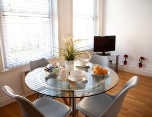 a dining room with a glass table and chairs at Apt 1, Opera House 2nd Floor by Indigo Flats in London