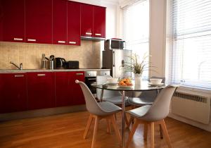 a kitchen with red cabinets and a table with chairs at Apt 1, Opera House 2nd Floor by Indigo Flats in London