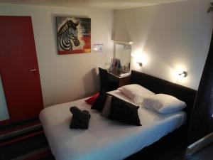 1 dormitorio con 1 cama con sábanas blancas y almohadas negras en Kyriad Direct Saintes, en Saintes