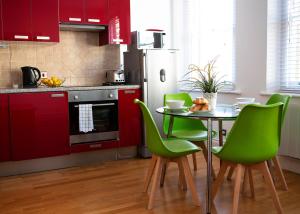 ロンドンにあるApt 2, Opera House by Indigo Flatsのキッチン(赤いキャビネット、テーブル、緑の椅子付)
