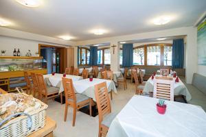 a dining room with white tables and chairs and a restaurant at PENSION KLUGHAMMER in Caldaro