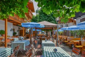 un restaurante al aire libre con sombrillas azules, mesas y sillas en Metzgerei Gasthof Oberhauser - Hotel zur Post, en Egling
