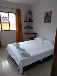 a bedroom with a bed with white sheets and a window at Hotel Lagos de Guatape in Guatapé