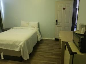 a bedroom with a white bed and a door at Budget Inn Hollywood in Los Angeles
