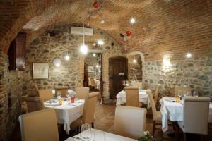 a restaurant with white tables and chairs and a brick wall at Locanda Osteria Marascia in Calolziocorte