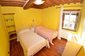 2 Betten in einem Zimmer mit gelben Wänden und einem Fenster in der Unterkunft Casa Daniel in Cappella