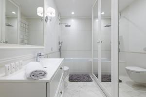 a white bathroom with a shower and a toilet at P&O Apartments Airport in Warsaw