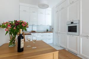 a white kitchen with a table with two glasses of wine at P&O Apartments Airport in Warsaw