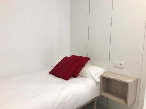 almohada roja sobre una cama blanca en Pitelos Apartment, en Santiago de Compostela