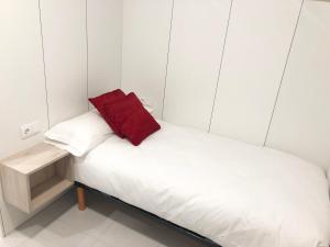 a small bed with a red pillow on it at Pitelos Apartment in Santiago de Compostela
