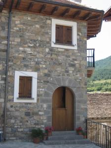 Edificio de piedra con 2 ventanas y puerta de madera en Casa Magdalena Autural, en Siresa
