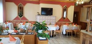 een restaurant met tafels en stoelen en een flatscreen-tv bij MyRooms - Margaretenhof in Erzhausen +6 foto's