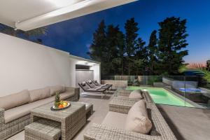 un soggiorno con divano, sedie e piscina di Luxury apartment SUNSET with private pool and jacuzzi a Novalja (Novaglia)