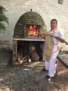 a man standing in front of a brick oven at Los Naranjos Hotel Boutique in Xalostoc