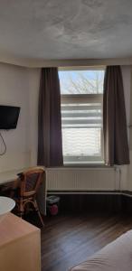 a bedroom with a window and a chair and a table at De Zevende Hemel in Kerkrade