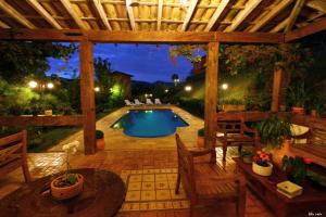 a backyard with a swimming pool and a wooden pergola at A Casa Vermelha Hospedaria in Tiradentes
