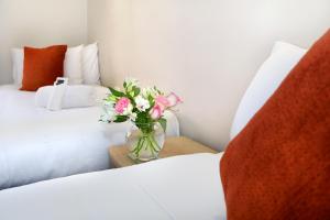 eine Blumenvase auf einem Tisch neben einem Bett in der Unterkunft Bella Vista Motel Invercargill in Invercargill