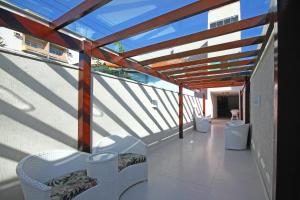 een balkon met witte stoelen en een glazen dak bij MDJ Pousada in Cabo Frio