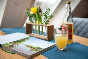 a glass of orange juice next to a book and a bottle at Urlaub Hamburg Altes Land in Hamburg