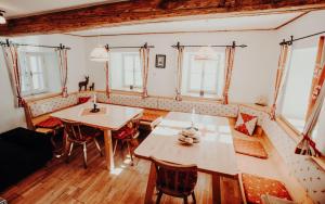 a dining room with two tables and chairs and windows at Stegerhütte in Hinterstoder