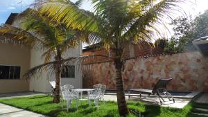 un patio con una mesa, sillas y una palmera en Casa Lazer, en Pirenópolis