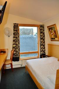 sypialnia z łóżkiem i oknem w obiekcie London Visitors Hotel w Londynie