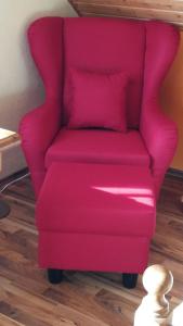 une chaise rose dans une chambre dotée de parquet dans l'établissement Gästehaus Moni Jäger, à Weyher