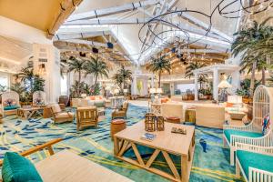 eine Lobby mit Tischen, Stühlen und Palmen in der Unterkunft Margaritaville Cottages Orlando with H2O Waterpark by Rentyl in Kissimmee