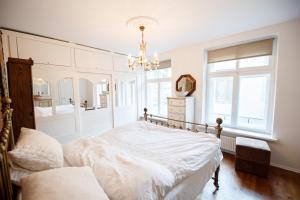 a white bedroom with a bed and a chandelier at Old Town Kalēju Street in Rīga
