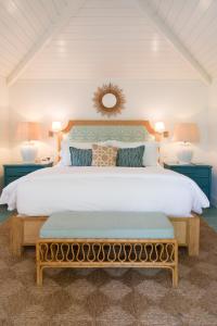a bedroom with a large white bed with a bench at Eleven Bahama House in Harbour Island