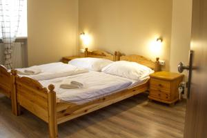 Un dormitorio con una gran cama de madera con sábanas blancas. en Pizzerie Jasany en Nový Šaldorf