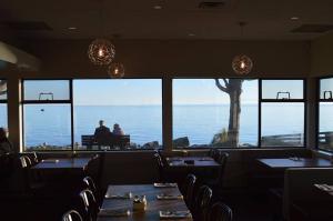 シーシェルトにあるDriftwood Innのテーブルと椅子が備わり、海の景色を望むレストラン