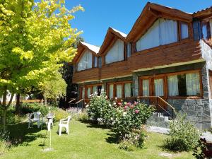 uma casa de madeira com um quintal com cadeiras e flores em De las Rosas Bariloche em San Carlos de Bariloche