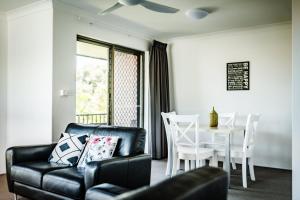 sala de estar con sofá, mesa y sillas en Coffs Harbour Holiday Apartments en Coffs Harbour