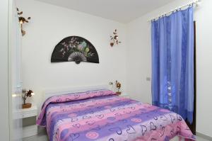 a bedroom with a bed with purple comforter and blue curtains at ISS Travel, Villa Fiorita - 800 m from La Cinta beach in San Teodoro